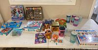 Wide view of lot with various puzzles, crafts, toys and game kits on table