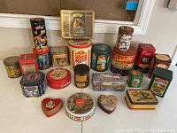Overview photo showing all the vintage advertising tins arranged together. Various brands and shapes visible.