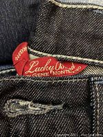 Close-up photo of red Lucky Brand label on dark blue denim women's jeans.