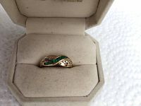 Top profile view of ring in open box showing green and white stones