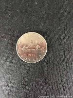 Obverse view of 1975 Canadian silver dollar coin displaying a canoe scene with paddlers and forest.
