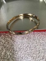 Full view of bangle resting on metal tray and textured surface