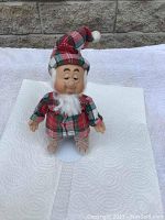 Front view of Sleepy dwarf figurine wearing red and green plaid outfit, facial expression sleepy, standing on a round metal base.