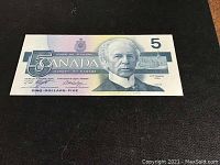 Front side of the 1986 Canadian five dollar note showing the portrait of Sir Wilfrid Laurier and denomination details.