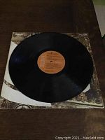 Vinyl LP record on top of the jacket showing the front cover and black vinyl disc.