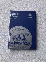 Blue coin collection binder titled 'Canada 5 Cents 1922-Date' with embossed beaver and leaf art.