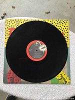 Black vinyl record featuring The Romantics label and Bomb Records branding placed on colorful pop art style sleeve.