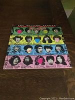 Photo of the two colorful album covers laid flat showing band member portraits and graphic design.