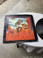 Top view of vinyl LP record cover showing colorful artwork and visible edge wear and creases.