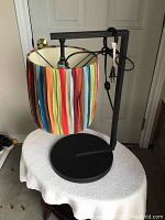 Front view of the modern end table lamp showing the multicolor striped shade and wrought iron base.