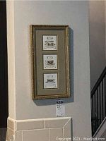 Framed art with three tea cup images hung on wall, gold frame with matting.