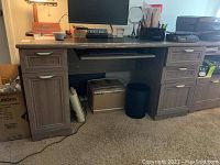Full view of computer desk showing faux leather top, left side cabinet with drawers and keyboard drawer, scratches, and veneer peeling.