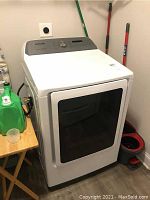 Front and side view of white Samsung front-load dryer in laundry room