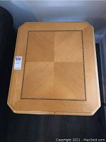 Top view of square wood table top showing checkered inlay pattern with detailed border.