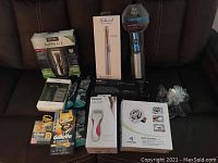 Full view of lot showing various boxed men's and women's personal care electric devices and disposable razors along with body slimmer device.
