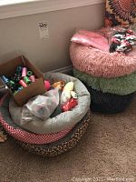Small pet beds in various colors and patterns along with a box of poop bags and dog toys