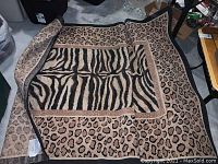 Leopard print area rug partially folded showing zebra pattern on the underside and leopard spots on top, placed on concrete floor.