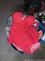 Red women's one-piece swimsuit with white polka dots and bow detail displayed in a basket.