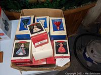 Box containing multiple Barbie-themed Hallmark Christmas ornament packages stacked together.