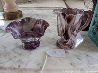 Two purple slag glass pieces on marble surface, one bowl and one pitcher