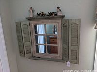 Wooden window-style decorative wall mirror with shutters, reflected furniture visible