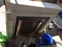 White electric fireplace mantle with decorative molding and a metal insert panel inside the firebox space.