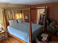 Full view of queen size four-poster bed with canopy rail, blue quilt, and white pillows in bedroom setting