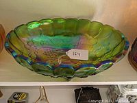 Top view of green carnival glass fruit bowl showing scalloped edges and grape pattern inside