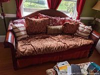 Front view of wooden daybed with paisley coverlet, bed skirt and decorative pillows