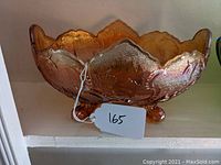 Front-angle view of marigold carnival glass bowl showing textured pattern, scalloped rim, and footed base.