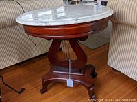 Front view of entire table showing white oval marble top and harp-shaped wood base