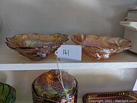 Pair of triangular carnival glass bowls on shelf showing iridescent and textured leaves and berries design.