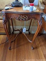 Full front view of one table showing carved apron, cabriole legs, stretcher and marquetry top edge