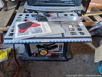 Full view of the Ryobi 10-inch table saw including the table surface, attached blade guard, and accessories laid on top.