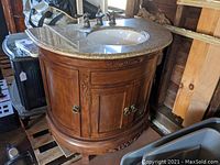 Full view of semi-circular wooden vanity showing carved detailing and granite countertop
