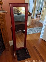 Full view of wooden standing cheval mirror with full-length mirror on front and reddish-brown finish.