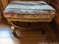 Side view of the vanity stool showing profile and upholstery with signs of wear and need for repair.
