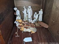 All Nativity scene figurines arranged inside wooden shelf including Mary, Joseph, shepherd, Wise Men, baby Jesus, and animals.