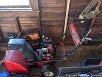 Full side view of the Yard Machines MTD snow blower showing red body, handle, chute, and tires.