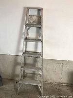 Front view of 6 foot aluminum step ladder showing five steps and flat top with paint splatters and scuffs.