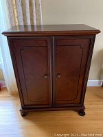 Front view of media cabinet with closed doors and round metal knob handles