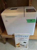 Charlescraft Deluxe Electronic Bread Maker unit shown with manual placed in front, featuring white exterior and control panel on lid.