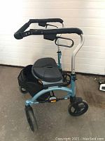 Side view of walker showing teal aluminum frame, black seat, front and rear wheels