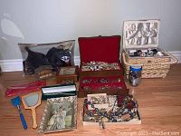 Overview of lot on wooden floor showing packaged bra, jewelry boxes, wicker basket and loose jewelry