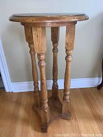 Side view of wooden plant stand table showing turned legs and base supports