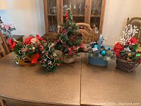 Photo showing all items on the table: 2 small Christmas trees and 3 decorative holiday baskets with various floral and festive accents.