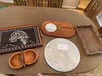 All items displayed together: two serving trays, two cheeseboards (one marble round and one wooden oval with marble inset), and one wooden nut dish with two compartments and handle.
