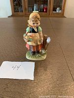 Figurine front view showing the girl with scarf, basket and bird with identification number 44 in photo
