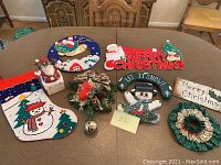 Table display of 5 Christmas wall hangings, stocking, and decorations.