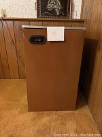 Brown compact dorm refrigerator closed, showing front with recessed handle and a paper with number 35.